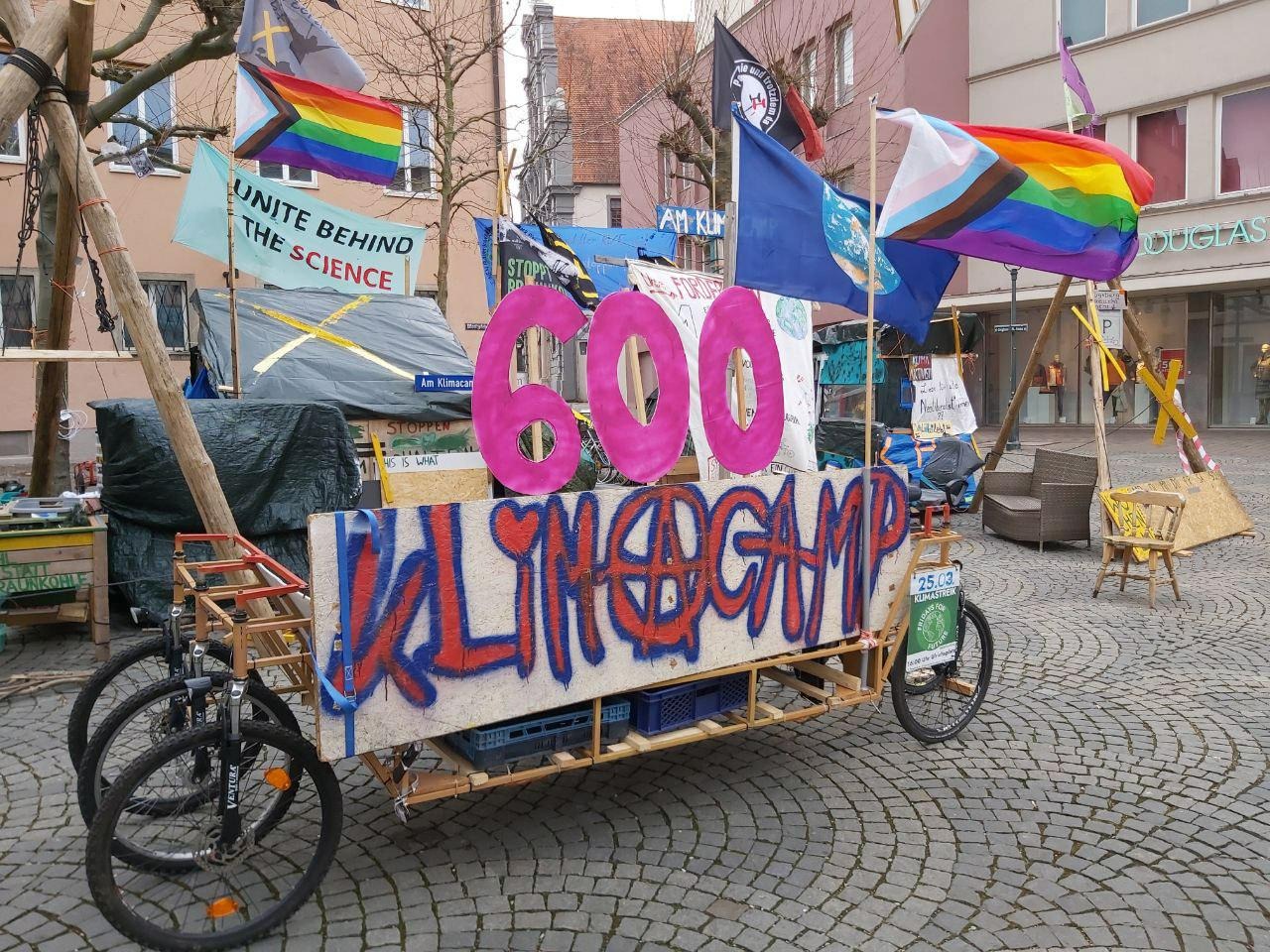 Foto des Augsburger Klimacamps an Tag 600: Die Zahl 600 ist auf einem Lastenfahrrad angebracht, welches vor dem Klimacamp steht.